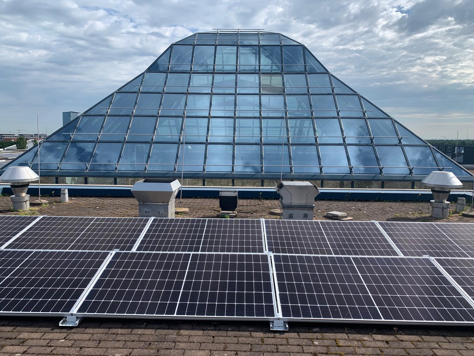 Photovoltaikanlage auf Flachdach vor moderner Glaspyramide – Architektur Design und Photovoltaik