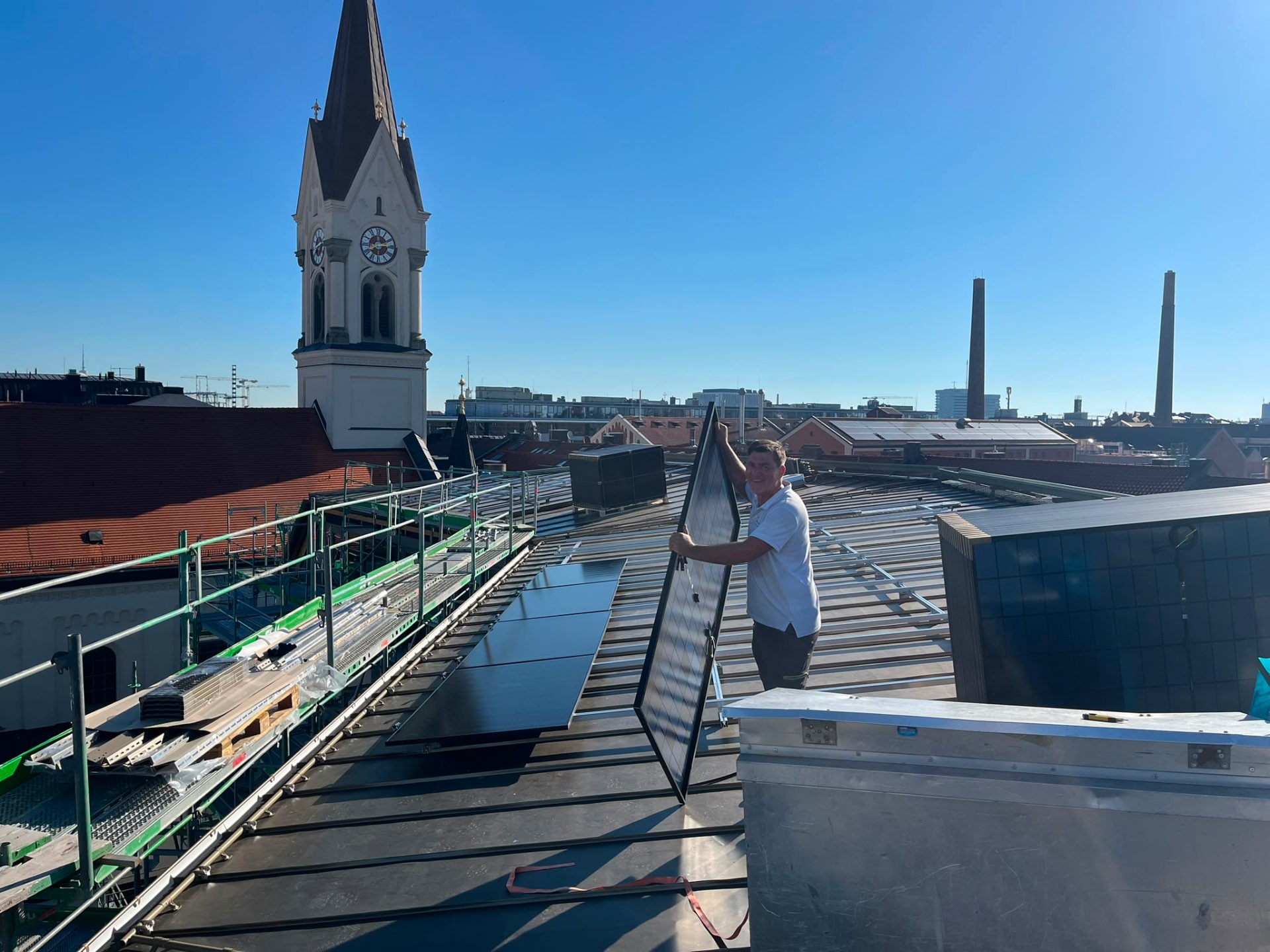 Solaranlagen-Montage auf einem Dach mit Kirchturm im Hintergrund – Tradition trifft Moderne