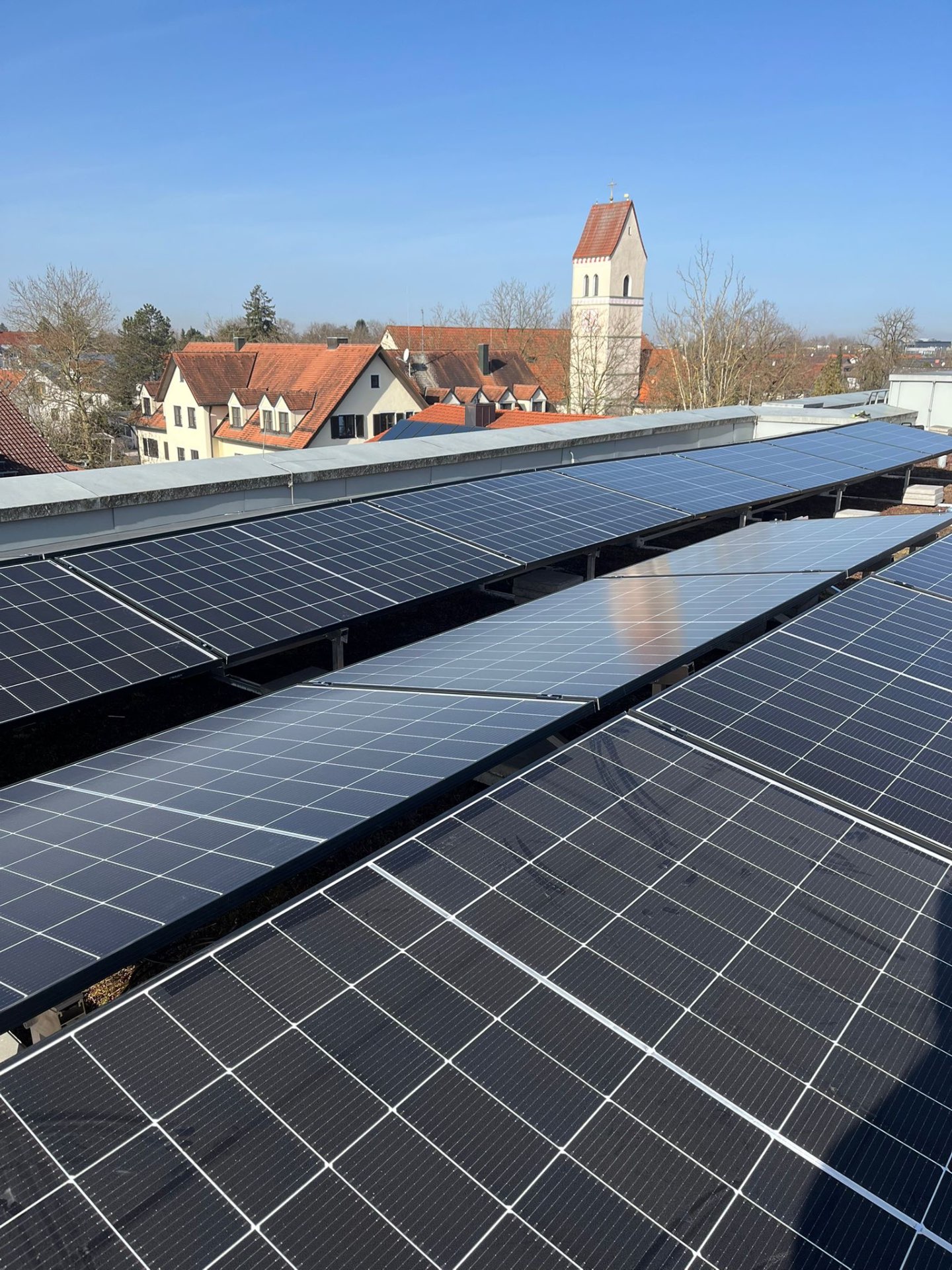 PV-Anlage auf Flachdach mit Blick auf bayerische Kirche