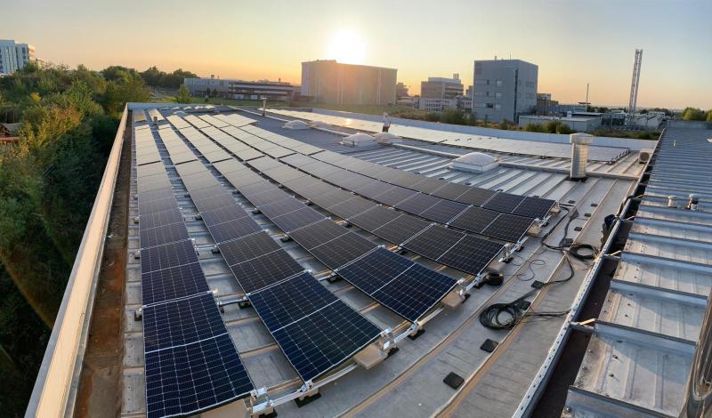 PV-Anlage auf Gewerbedach im Sonnenuntergang mit Stadtkulisse