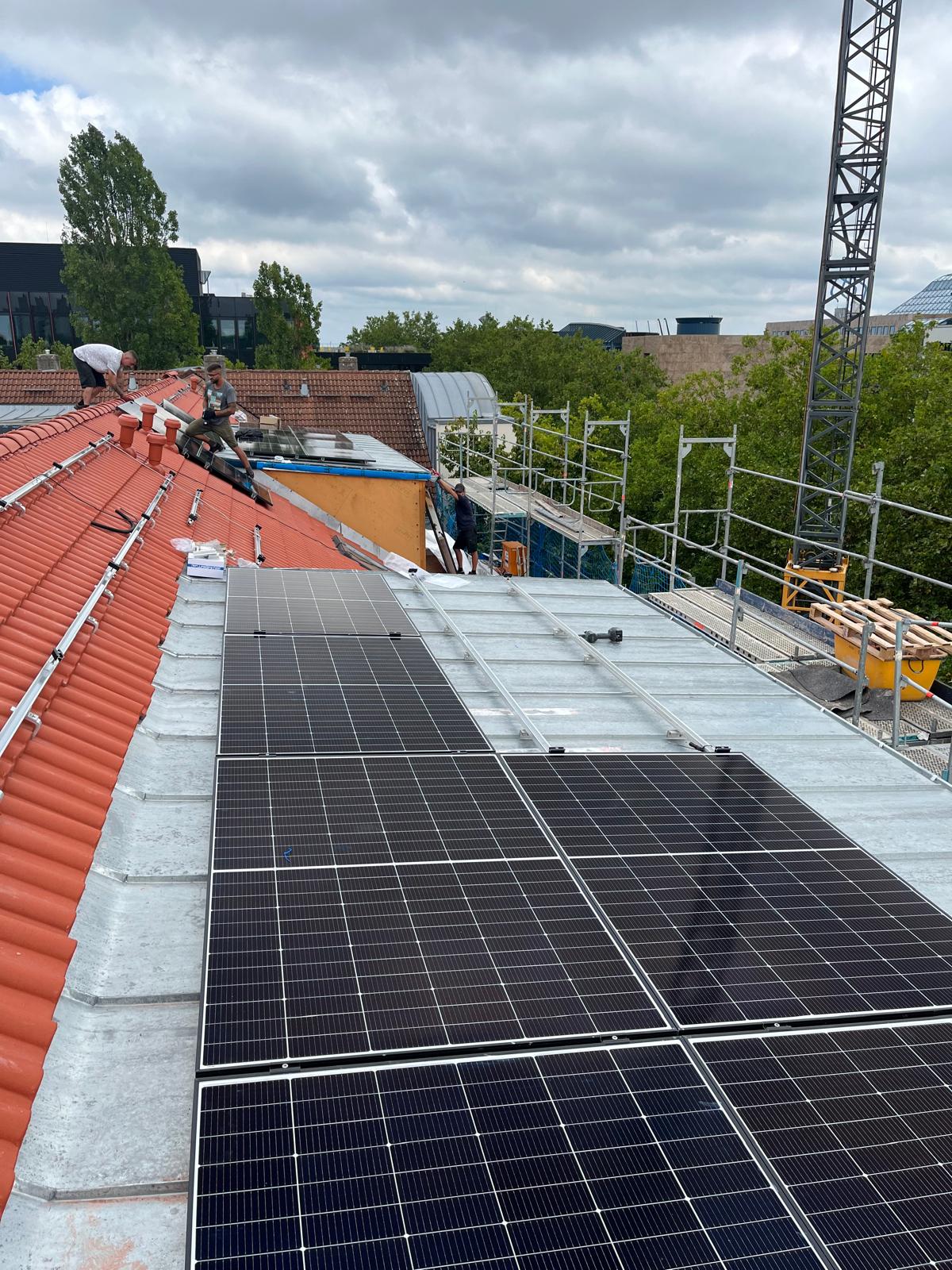 PV-Module auf Steildach mit Monteuren und Baukran