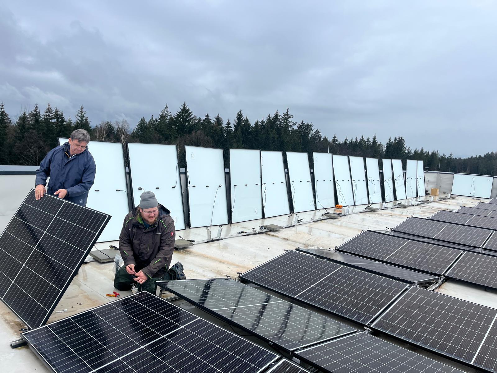 Monteure installieren PV-Module auf großem Flachdach